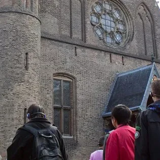 Kinderen luisteren aandachtig naar een rondleiding in het museum.
